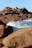 A person standing on a rocky beach next to the ocean