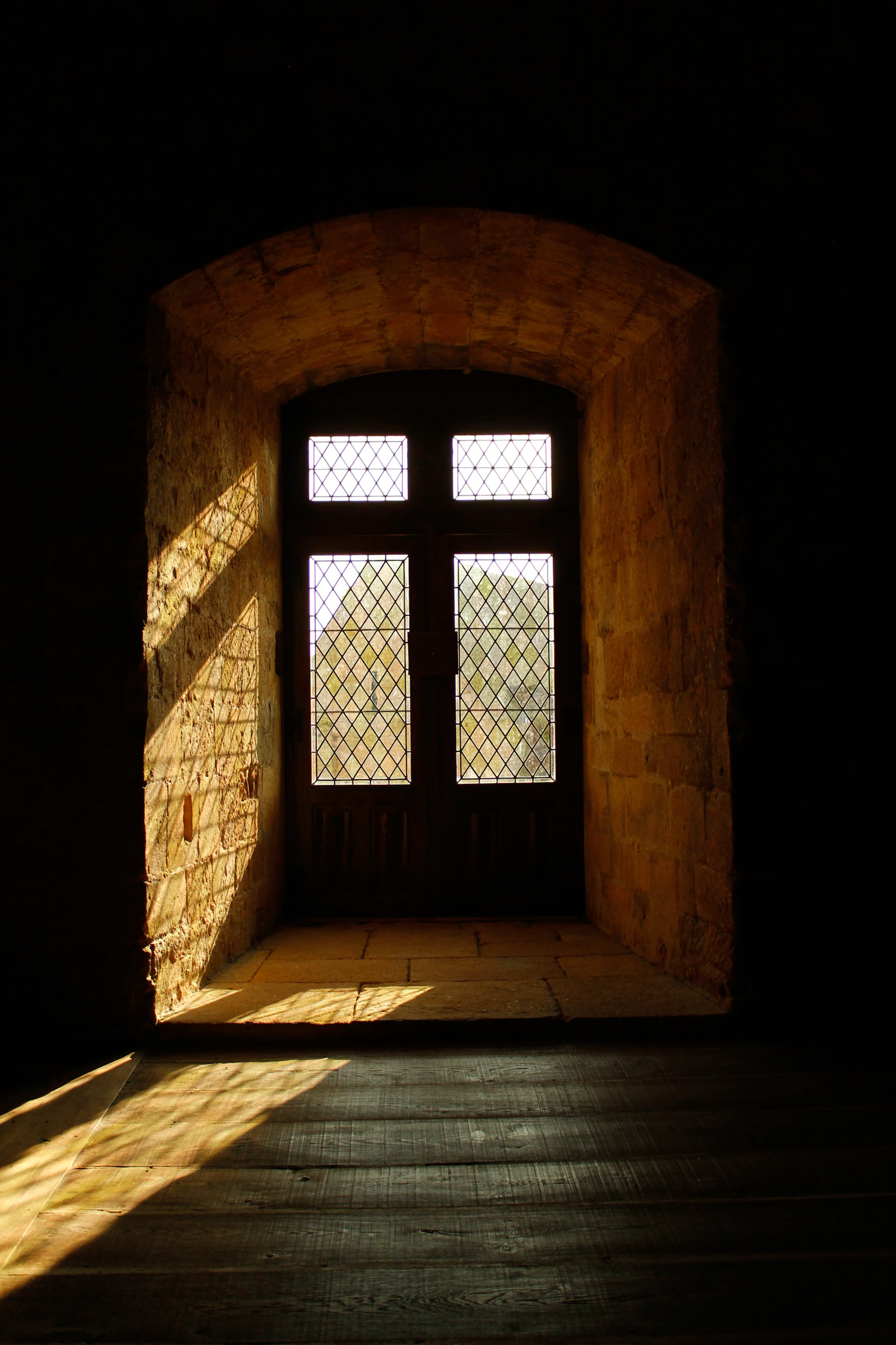 A dark room with a window and a wooden floor