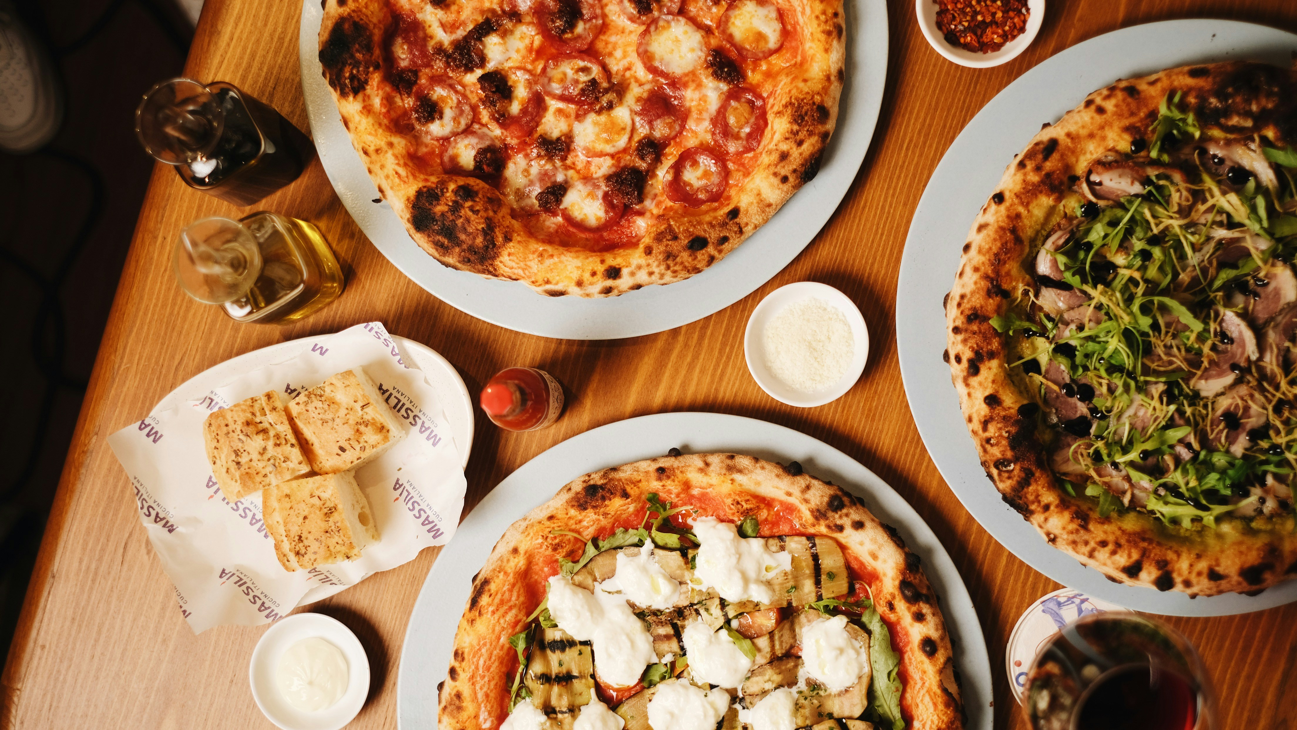 A table topped with three pizzas covered in toppings