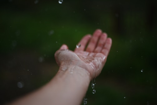 A person holding their hand out in the rain