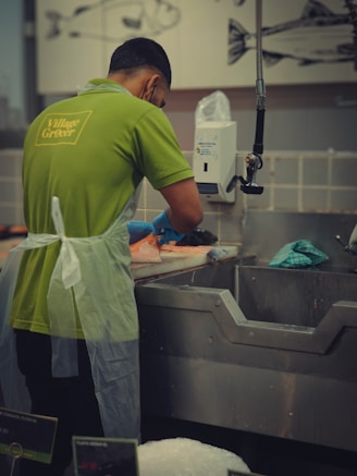 A man in a green shirt washing dishes in a kitchen