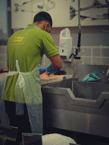 A man in a green shirt washing dishes in a kitchen