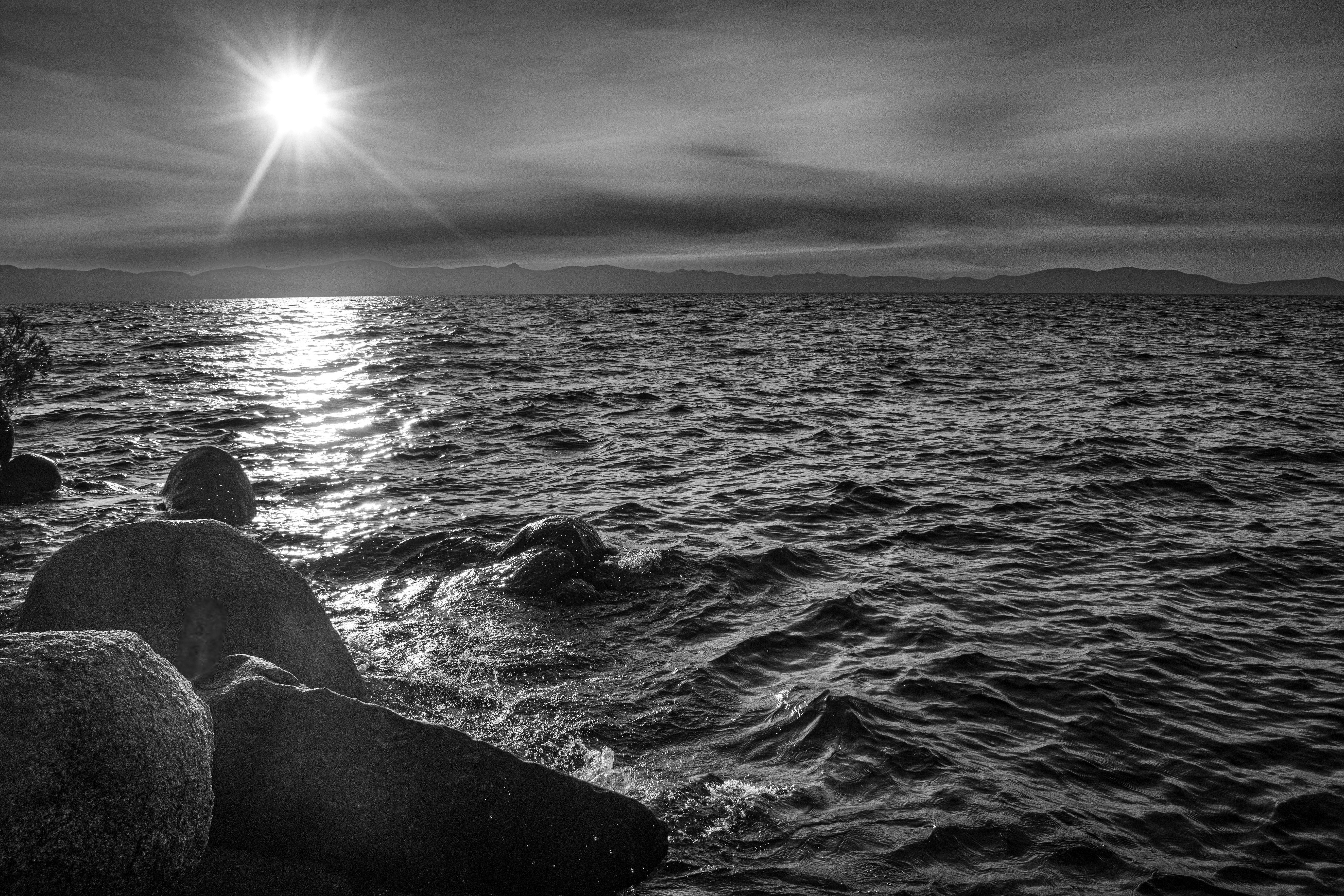 A black and white photo of the sun setting over the ocean