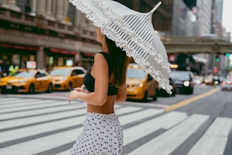 A woman walking across a street holding an umbrella