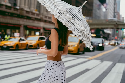 A woman walking across a street holding an umbrella
