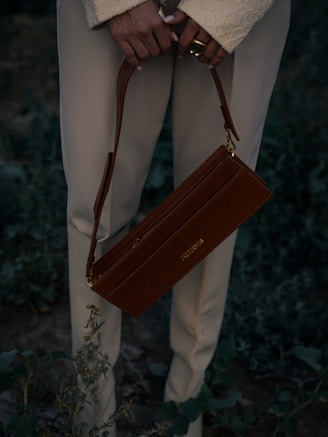 A woman holding a brown purse in her hands