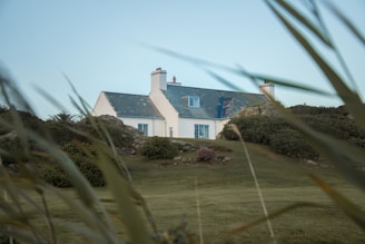 A white house sitting on top of a lush green field
