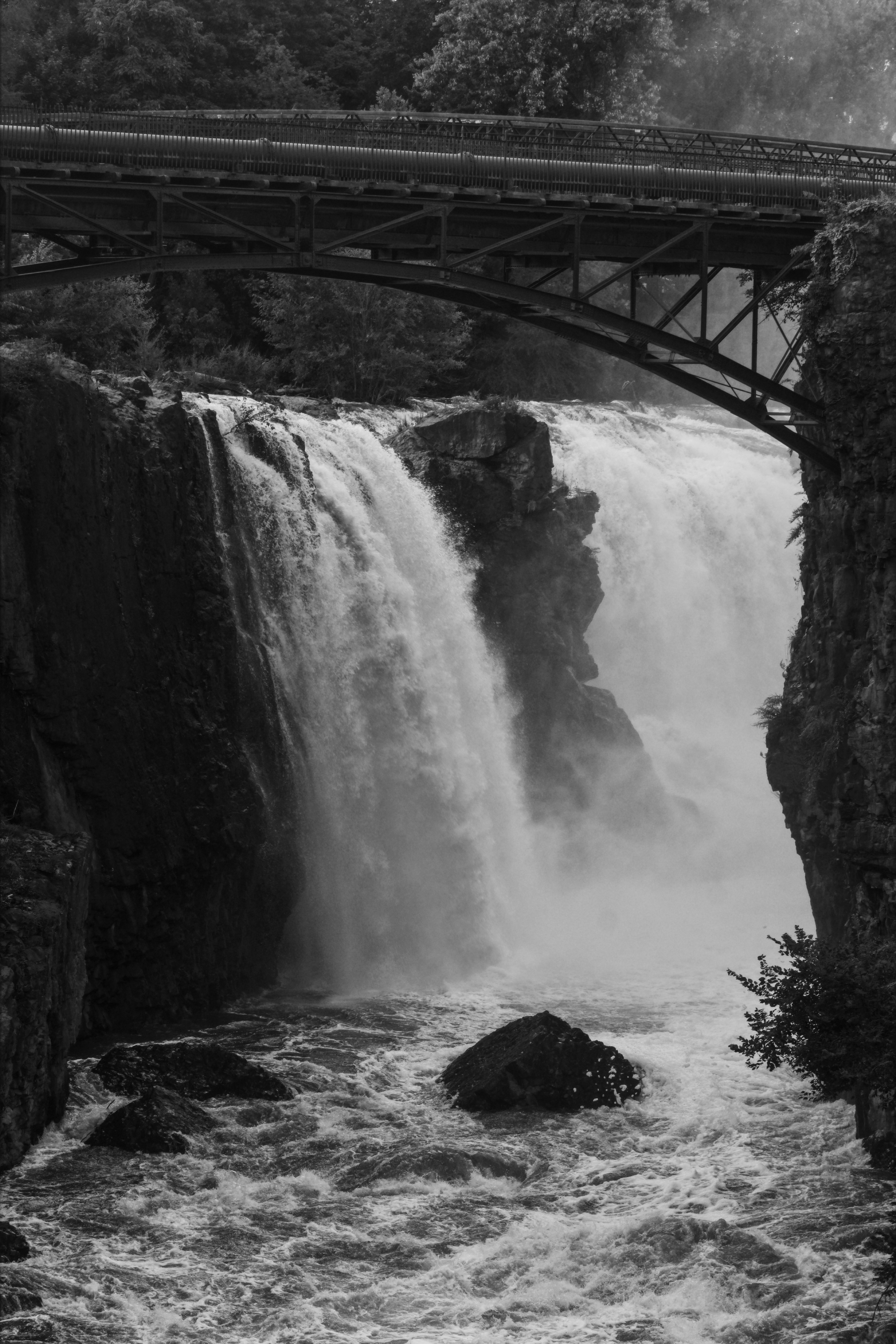 A black and white photo of a bridge over a waterfall