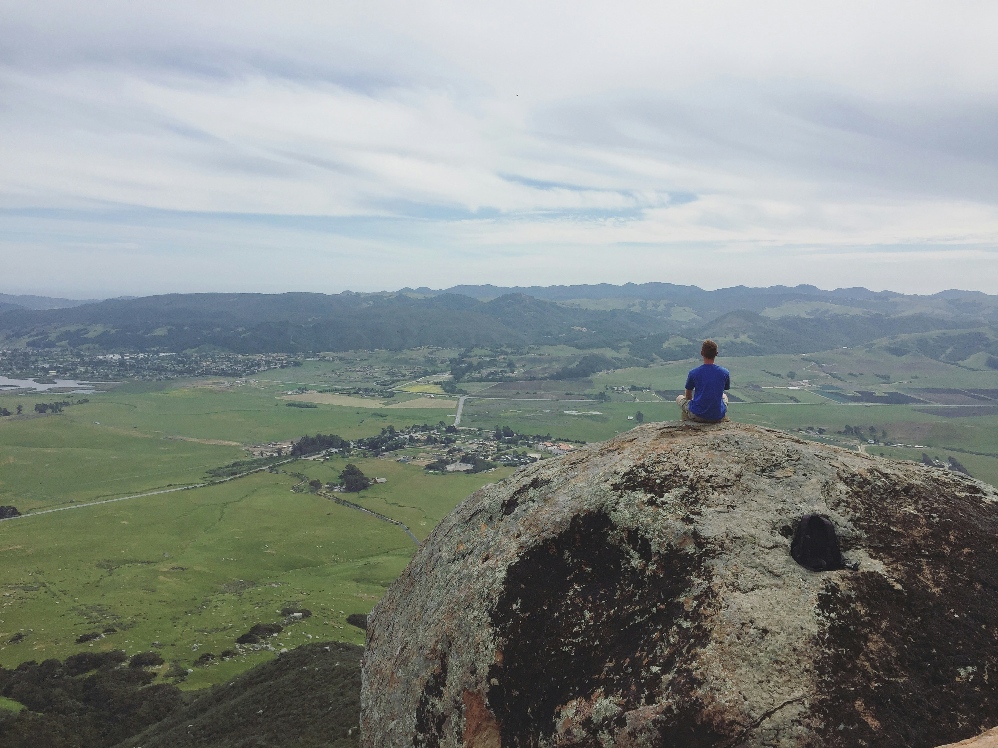 A person sitting on top of a large rock