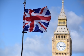 A british flag flying in front of the big ben clock tower