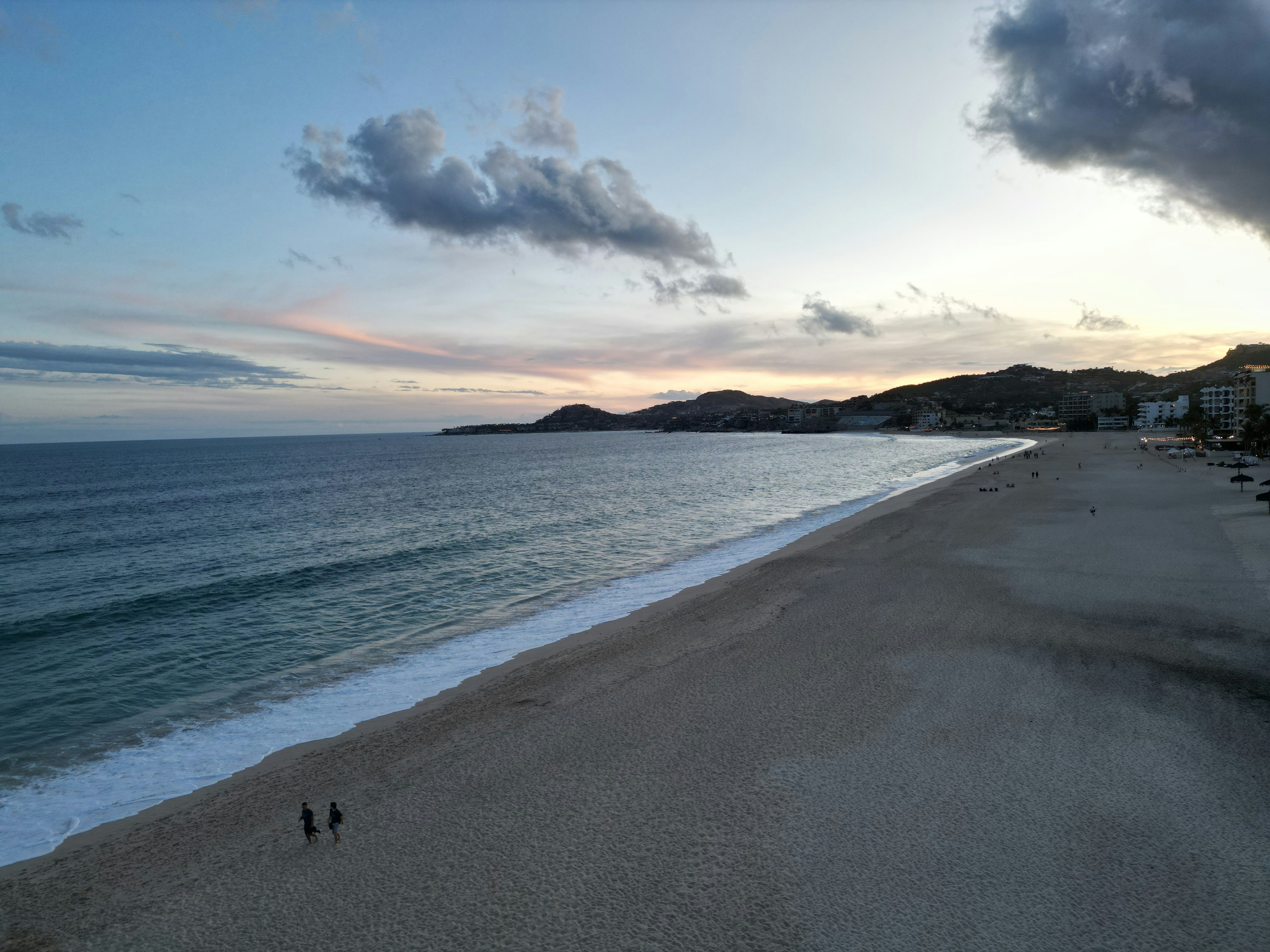 A beach with a couple of people walking on it