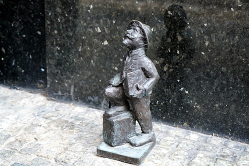 A statue of a boy standing next to a building