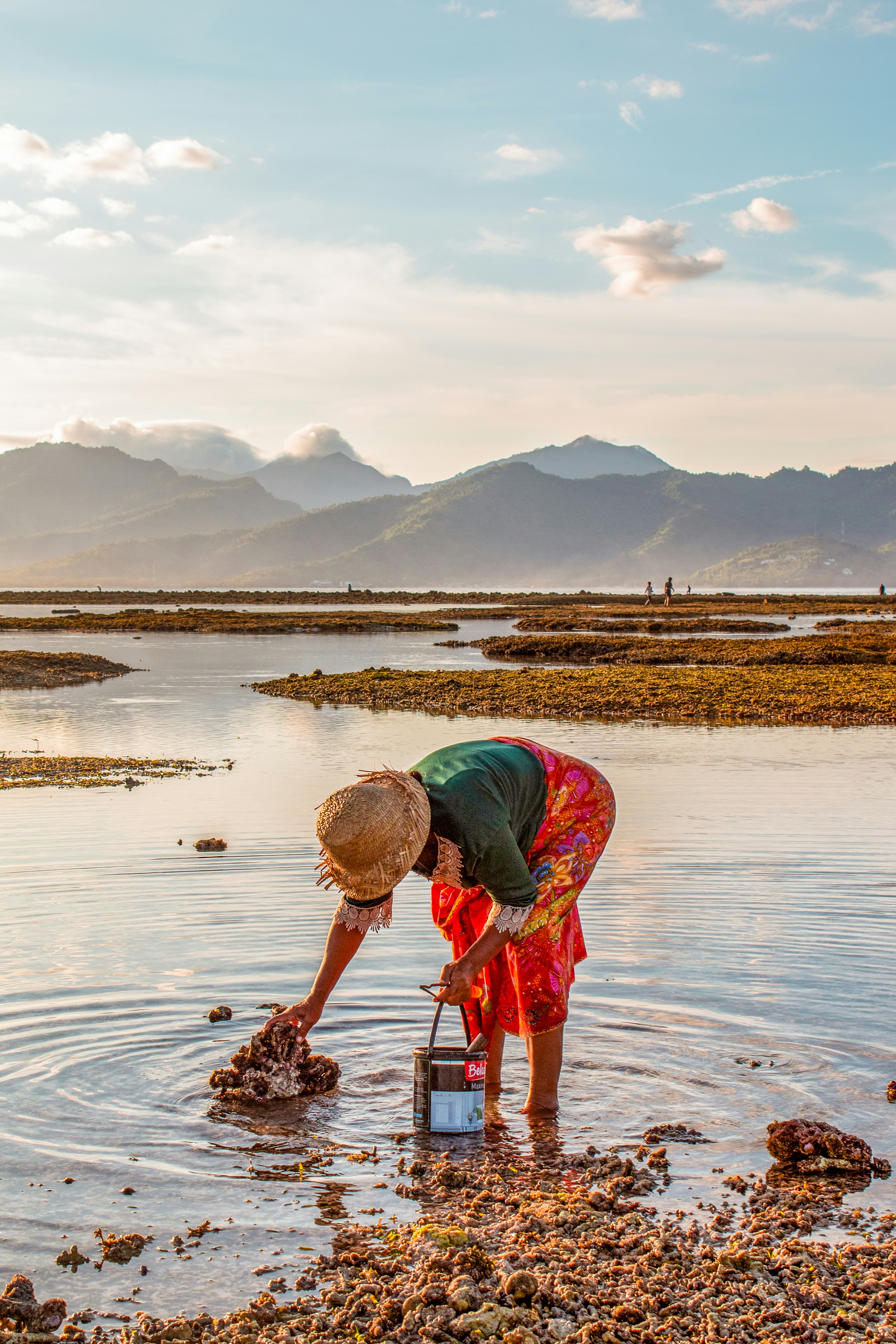 A person standing in a body of water with a bucket