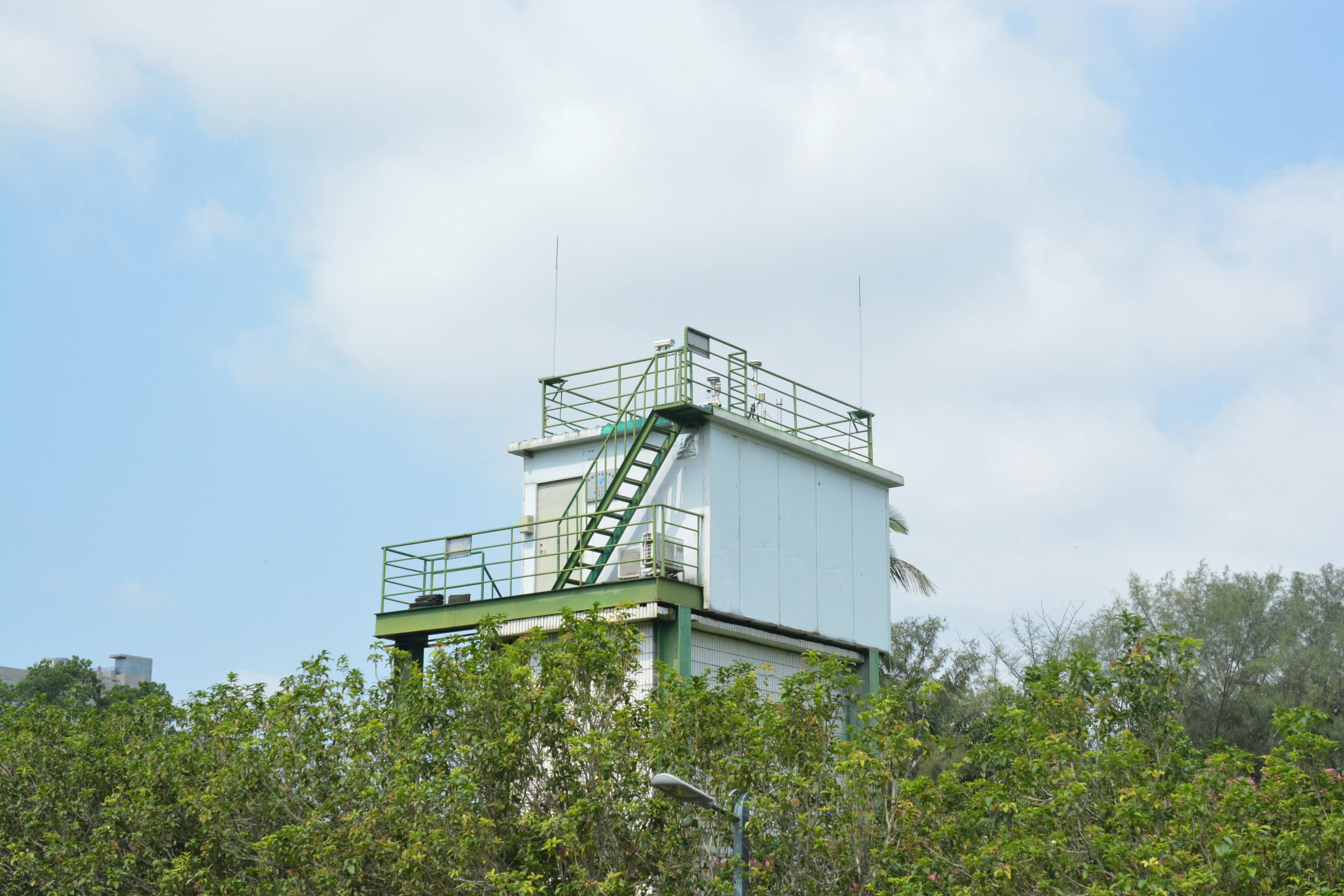 A green and white tower sitting on top of a lush green forest