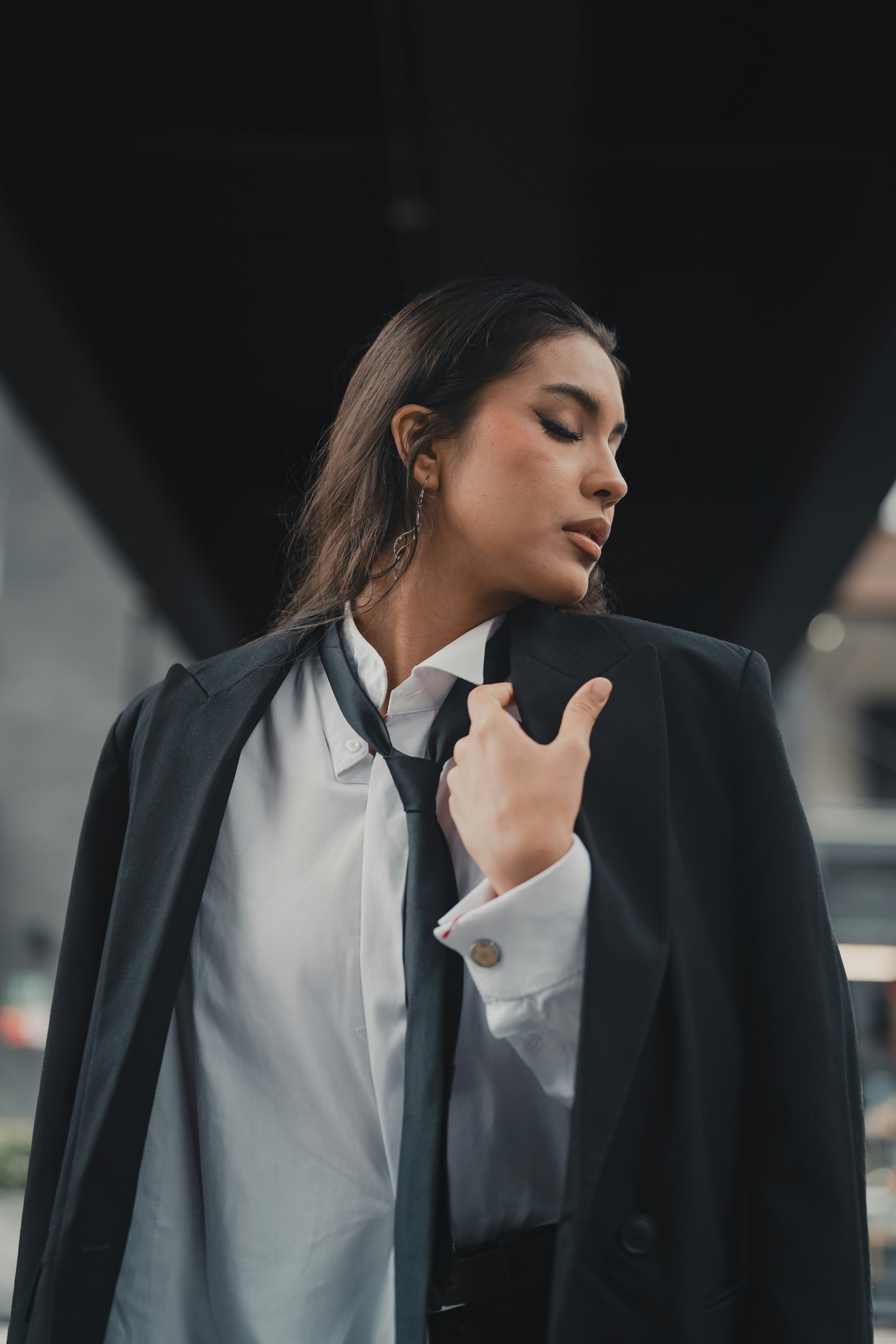 Eine Frau in Anzug und Krawatte steht vor einem Gebäude