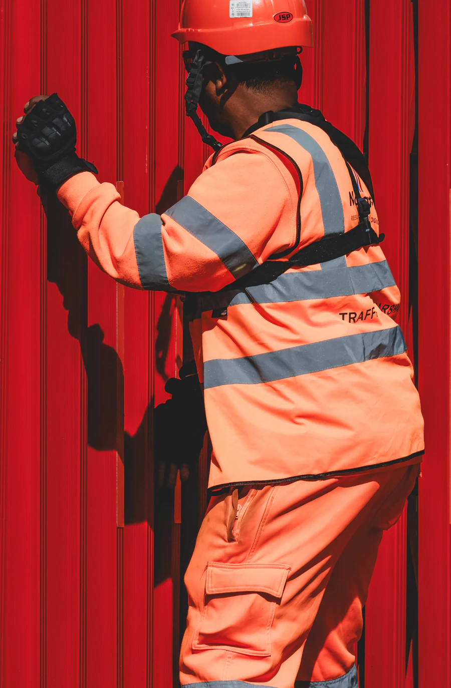 Industrial worker wearing a high-visibility orange safety jacket and helmet — corporate workwear sourcing