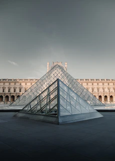 A large building with a glass pyramid in front of it