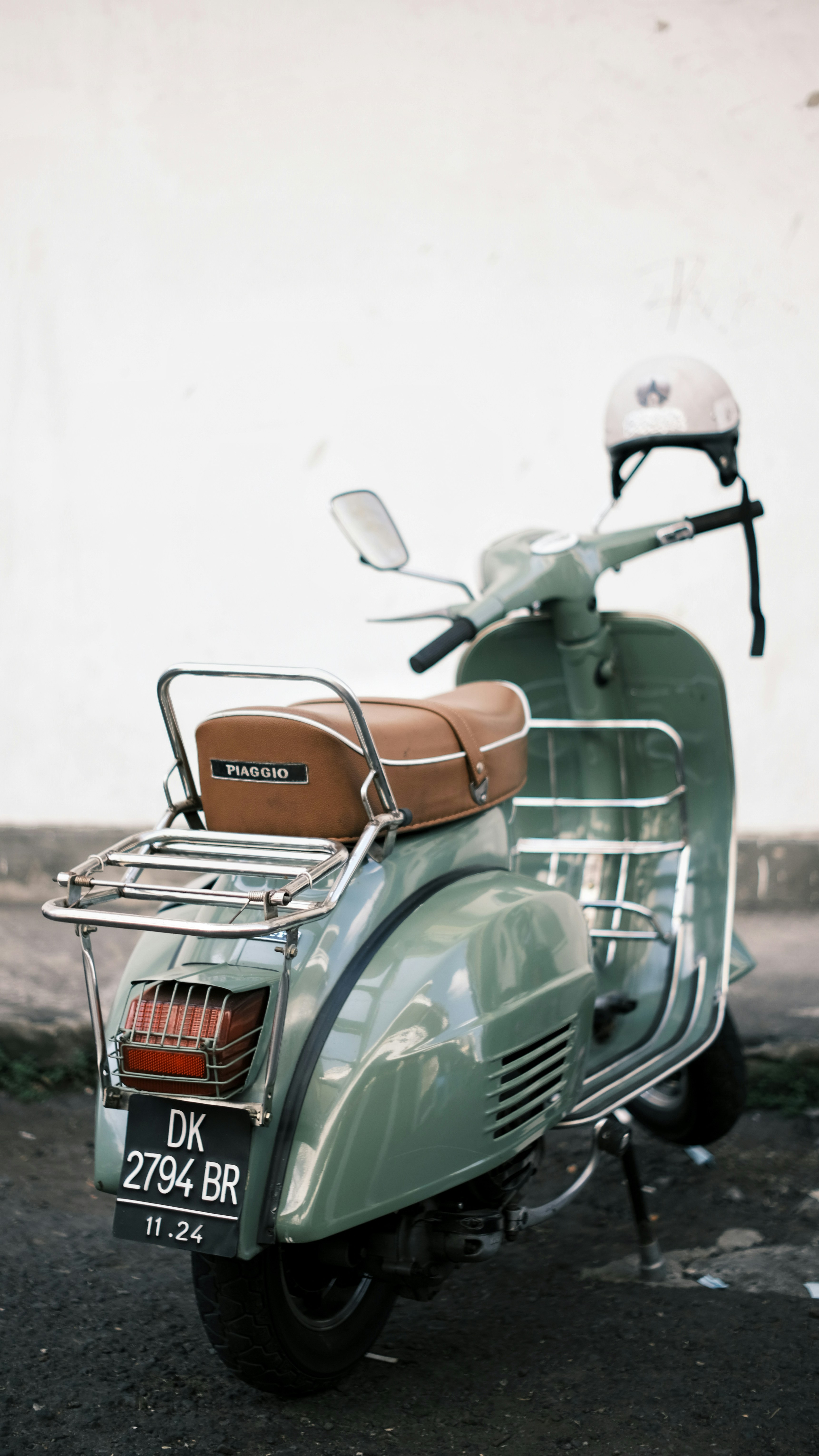 A green scooter parked on the side of the road