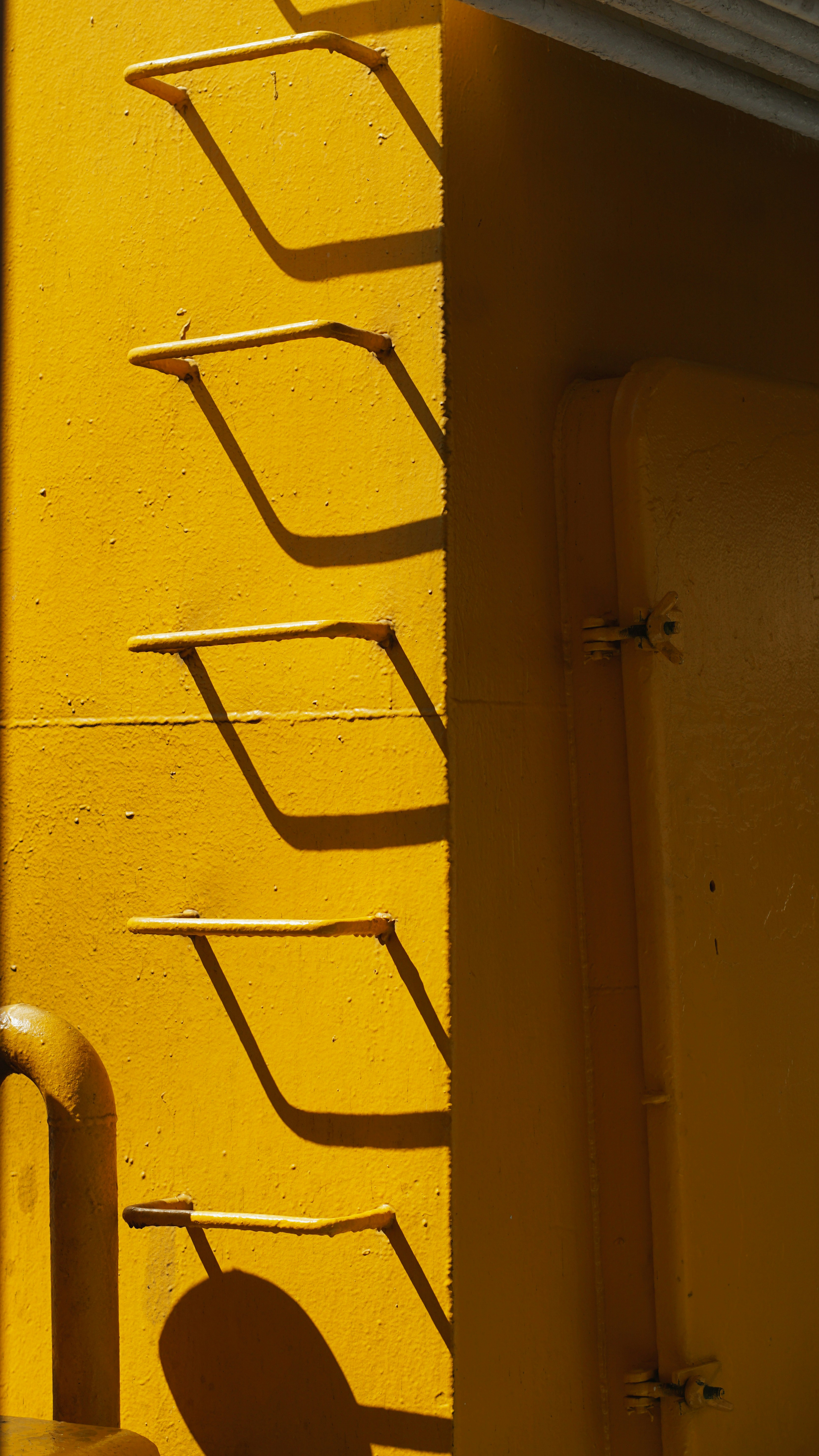 A close up of a yellow wall with a metal handle