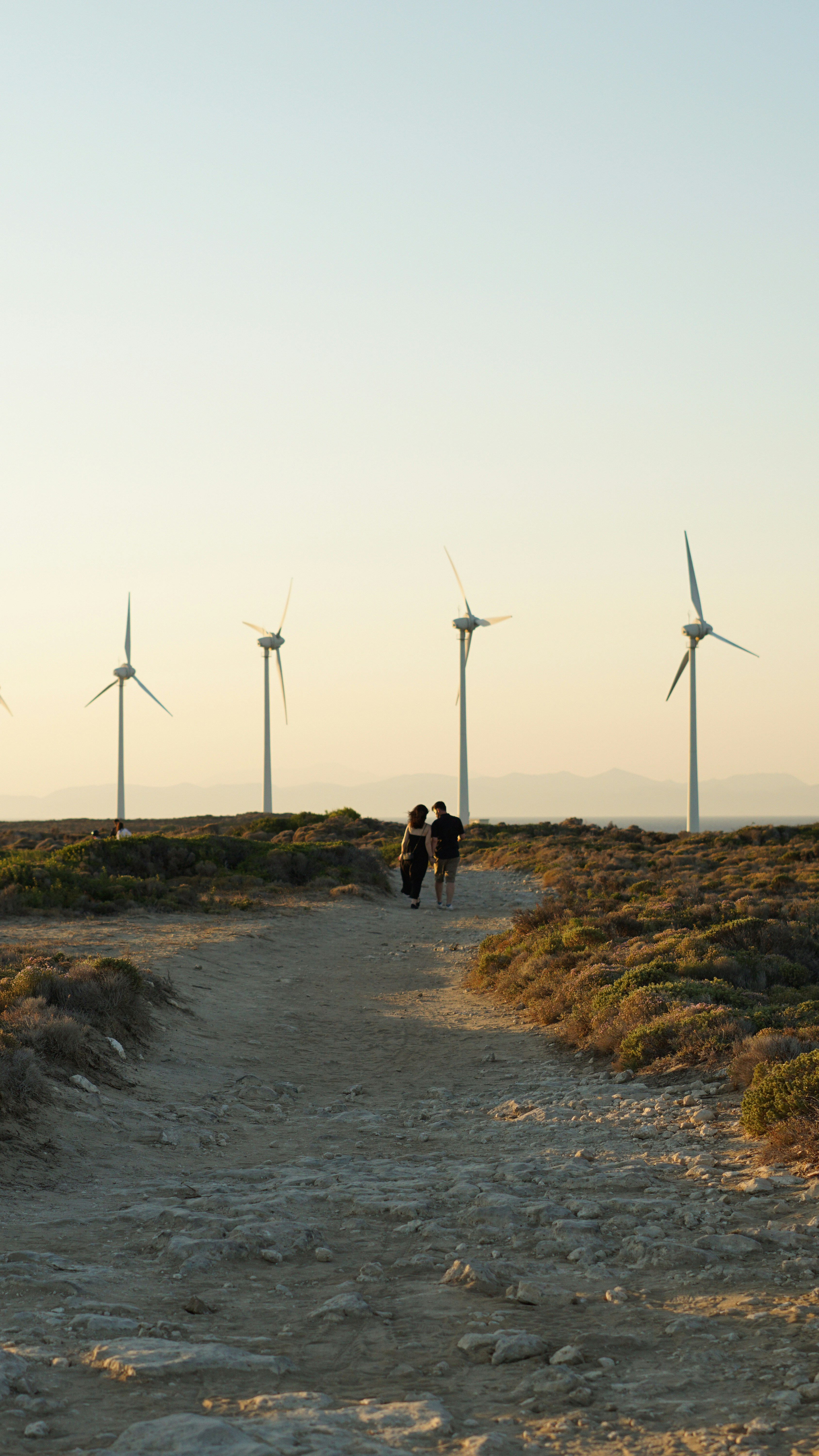A couple of people walking down a dirt road