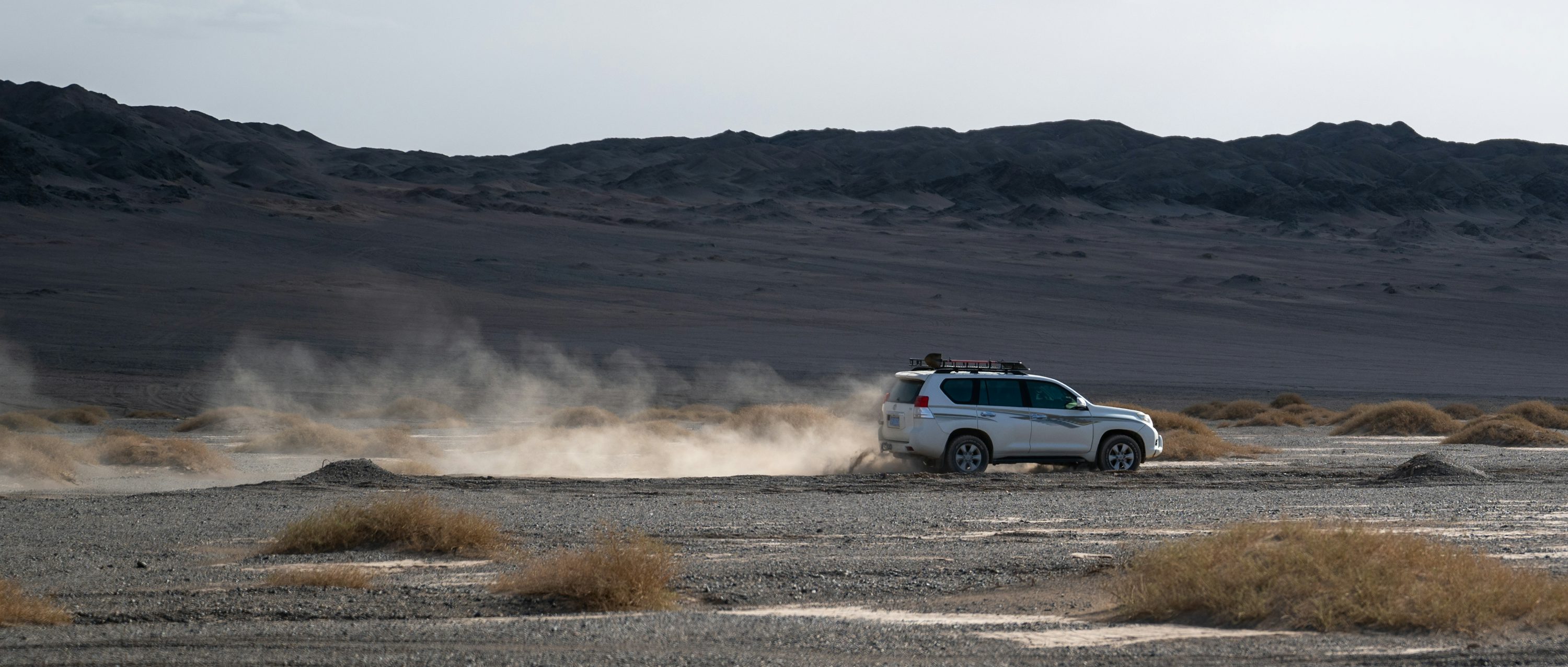 A white truck driving down a desert road