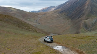 A car driving down a dirt road in the mountains