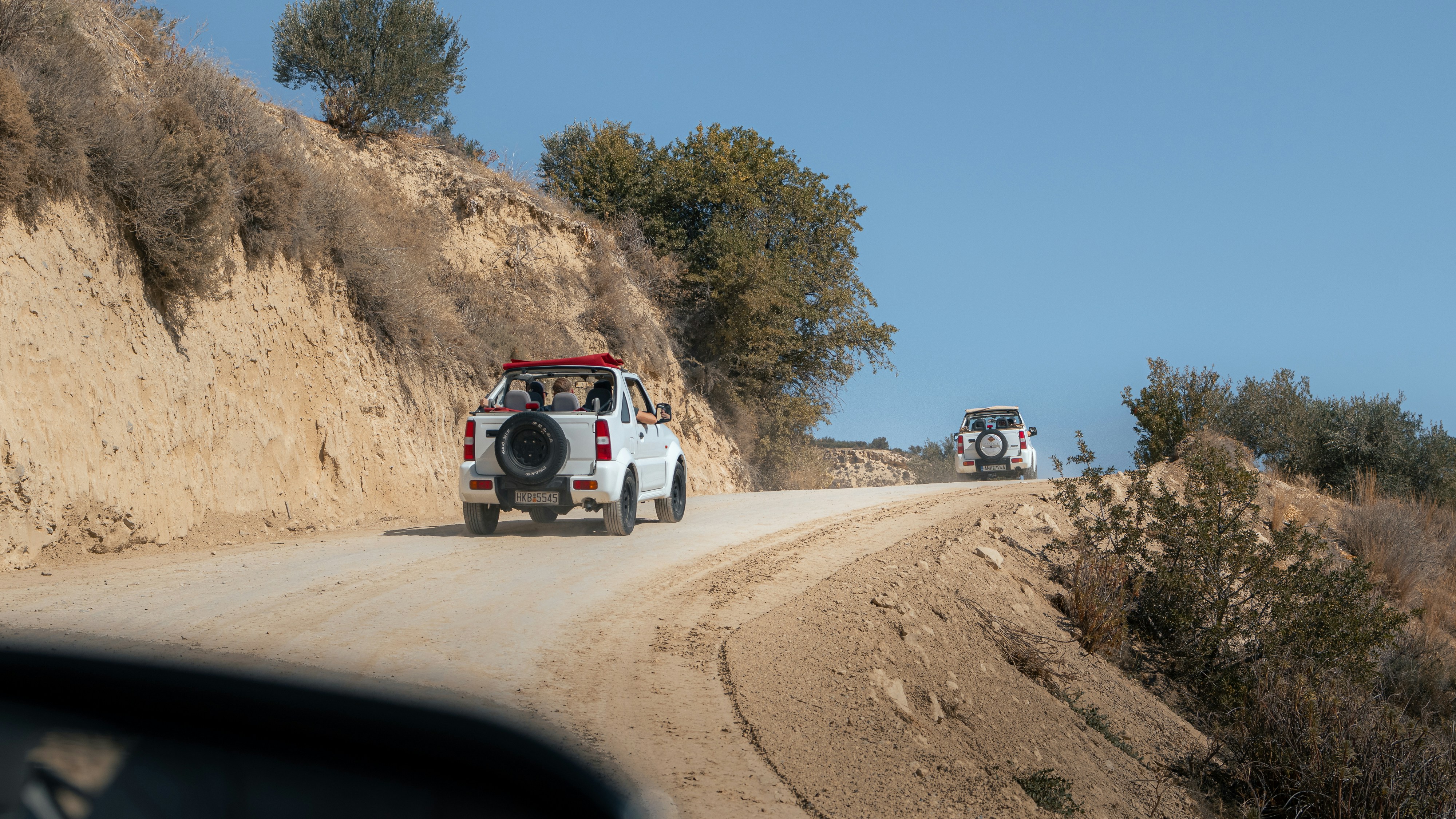 A car driving down a road next to a cliff, 