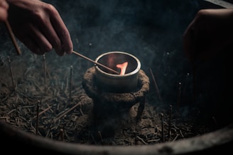 A person lighting a candle in a bowl