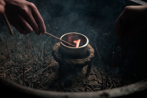 A person lighting a candle in a bowl