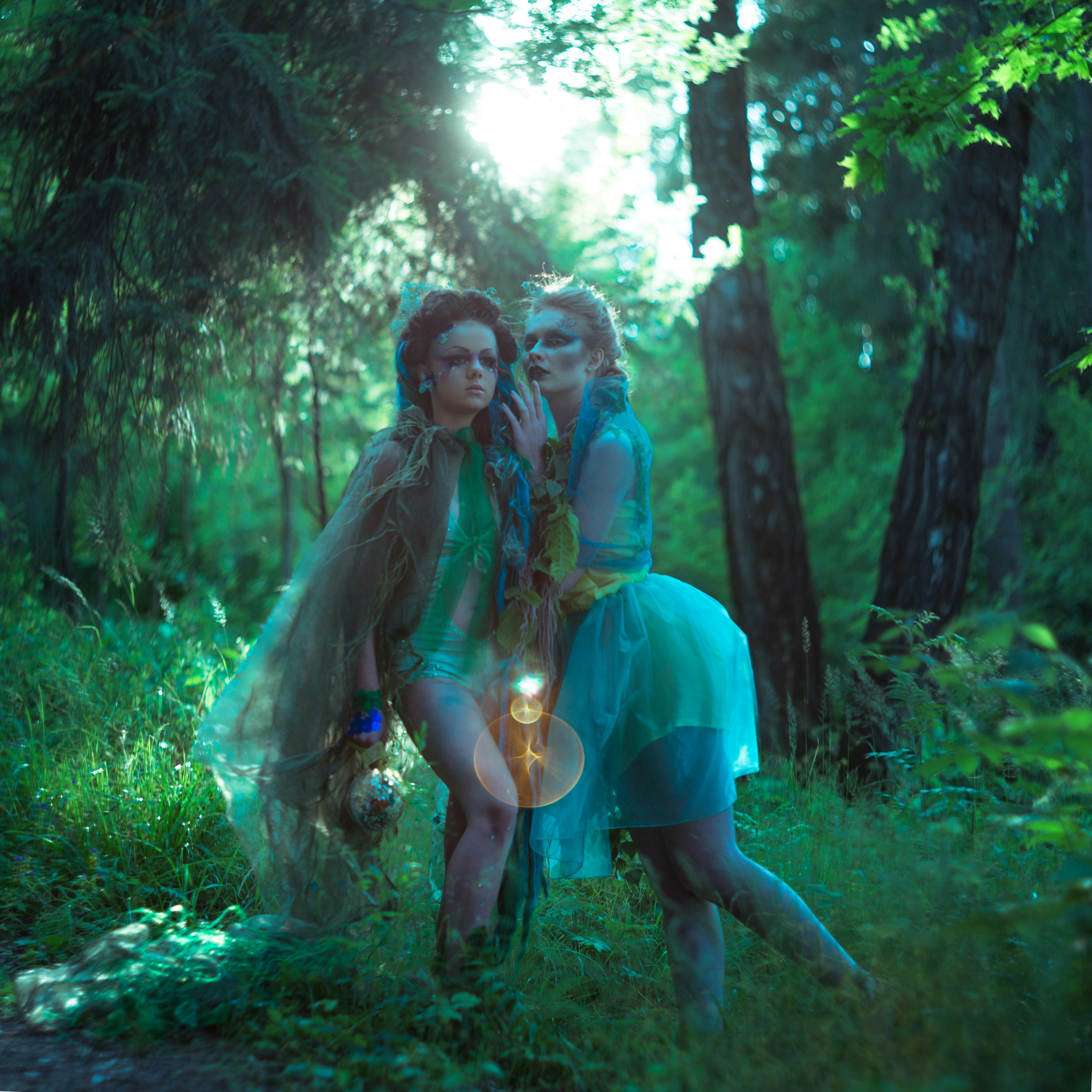 Two women in blue dresses standing in the woods