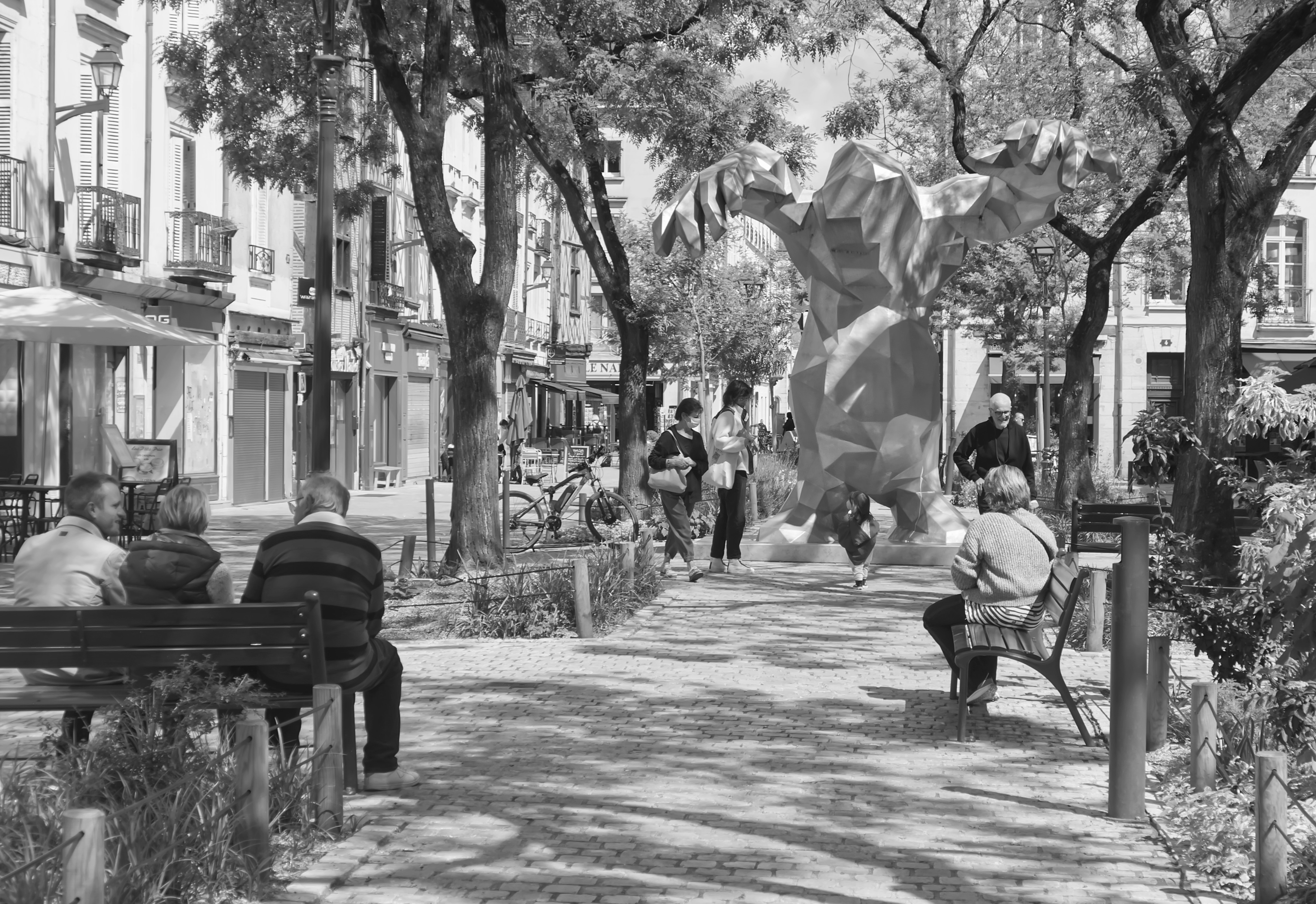 A black and white photo of people sitting on a bench