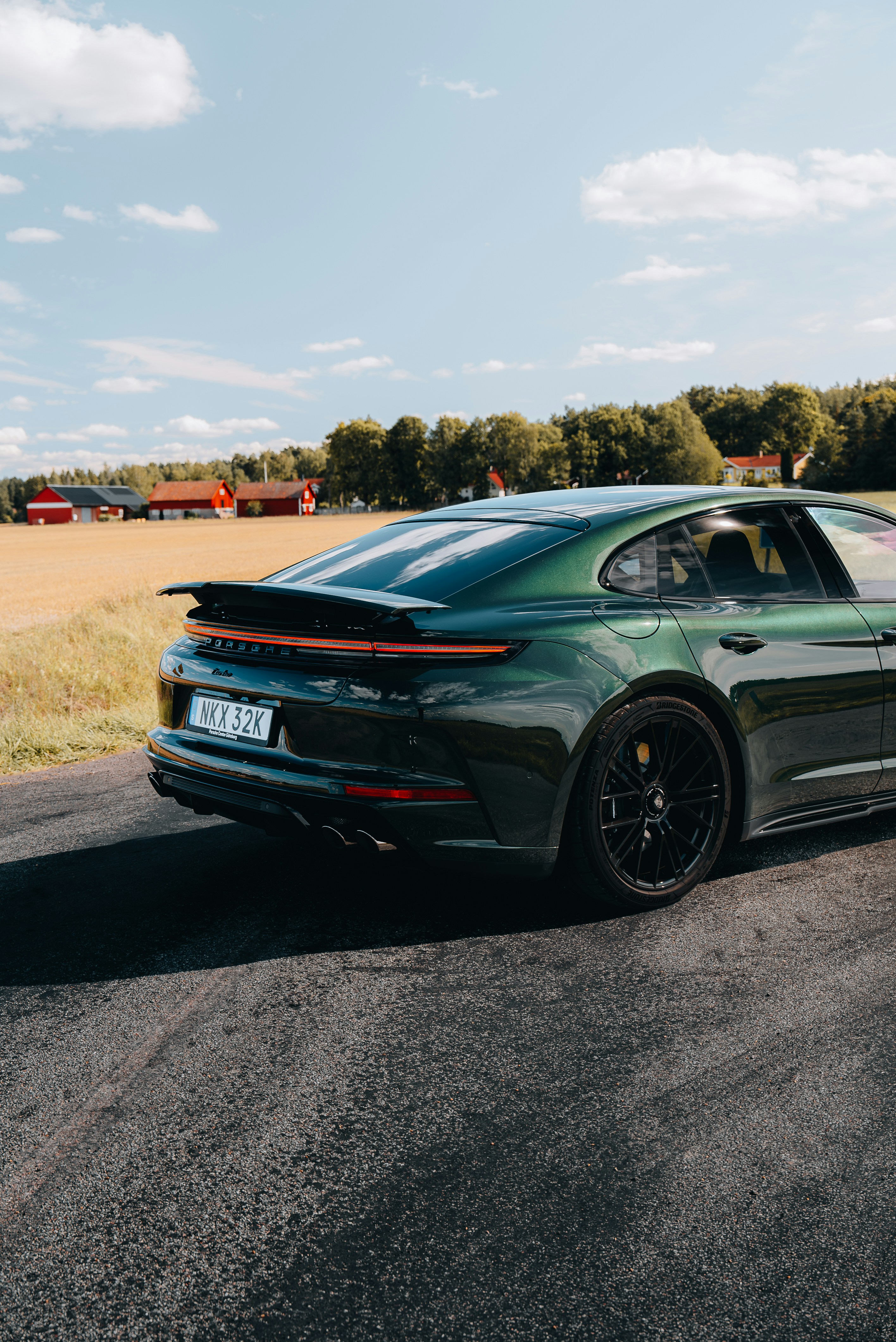 A green sports car driving down a rural road