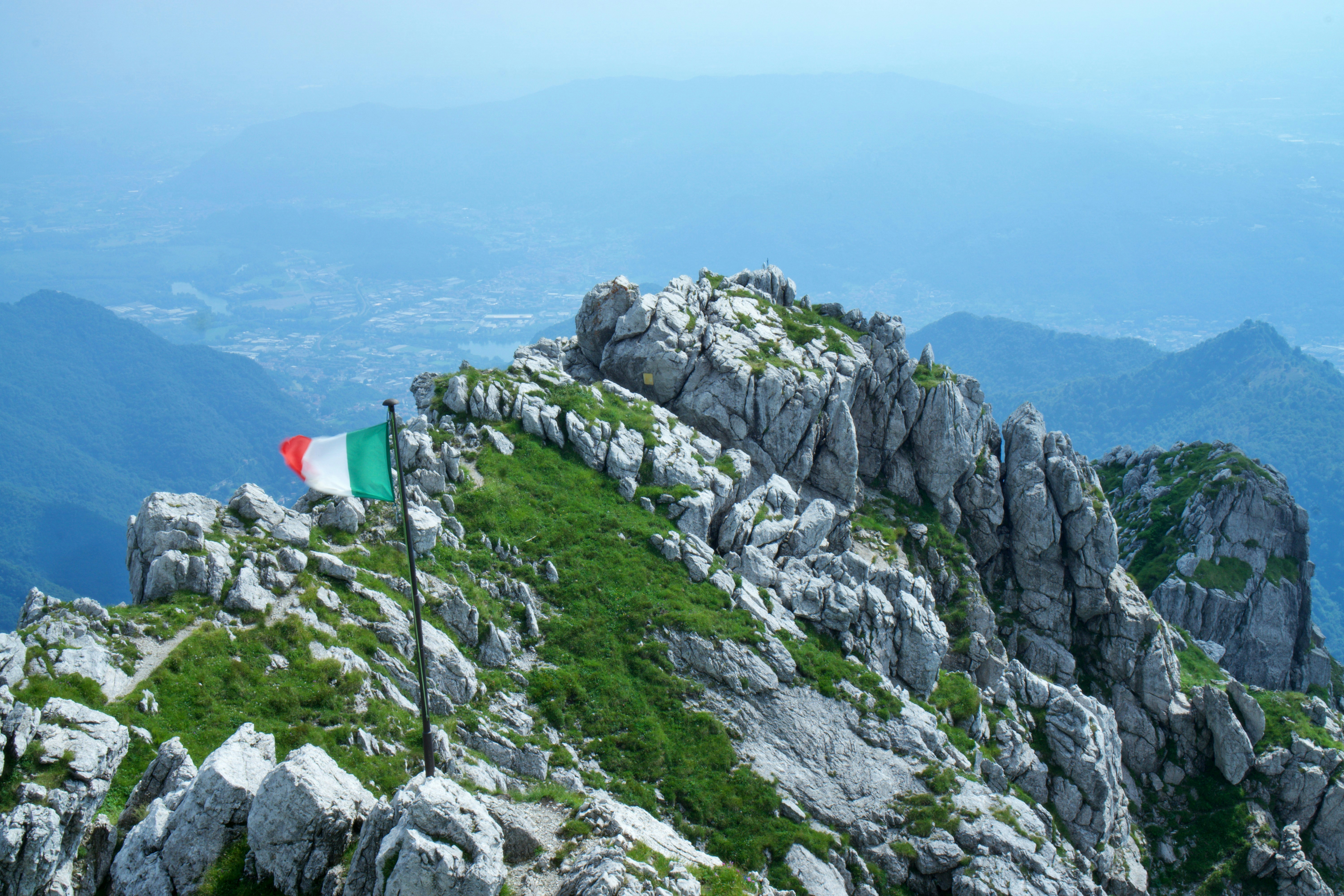 A flag on top of a mountain with mountains in the background