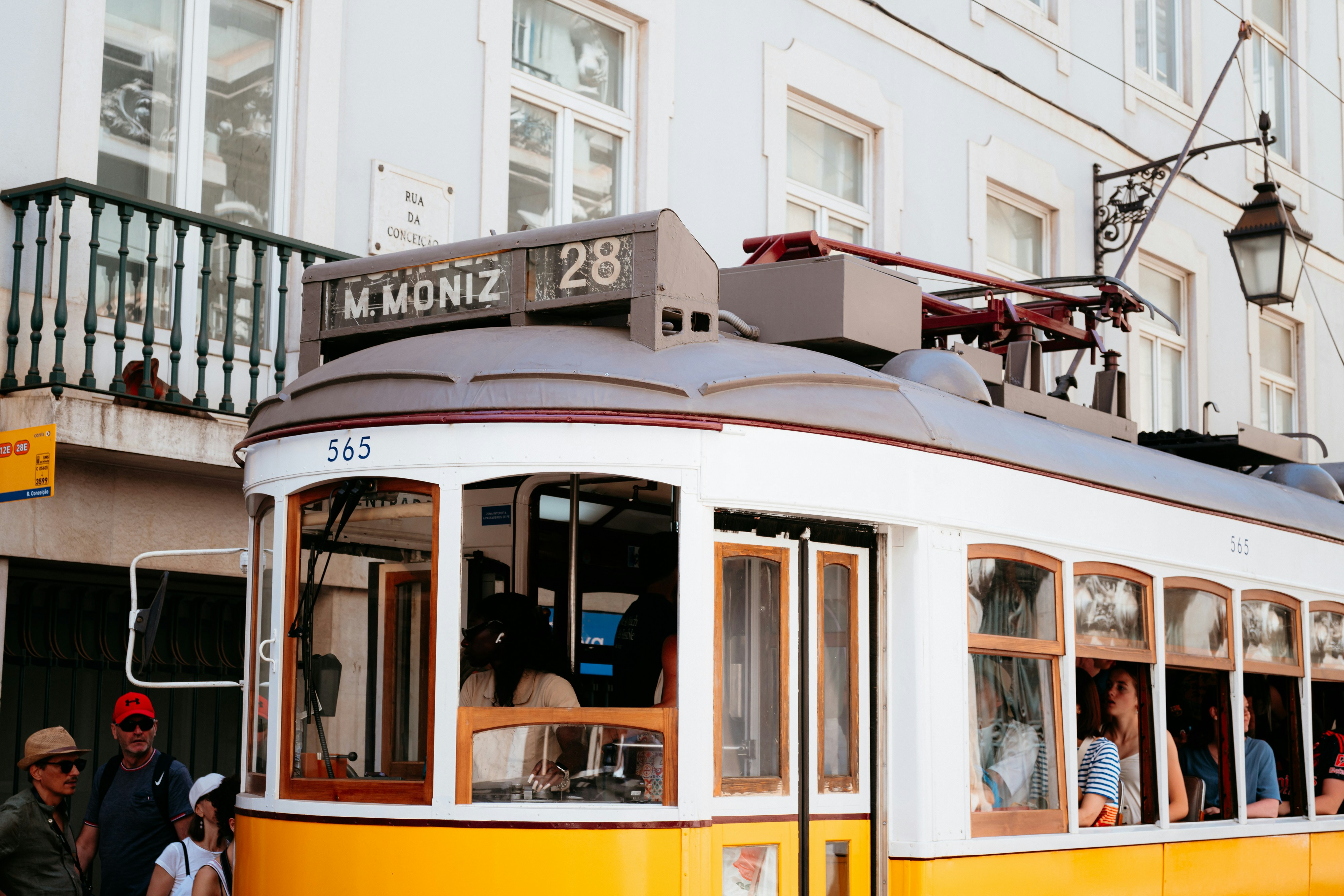 A yellow and white trolley car traveling down a street