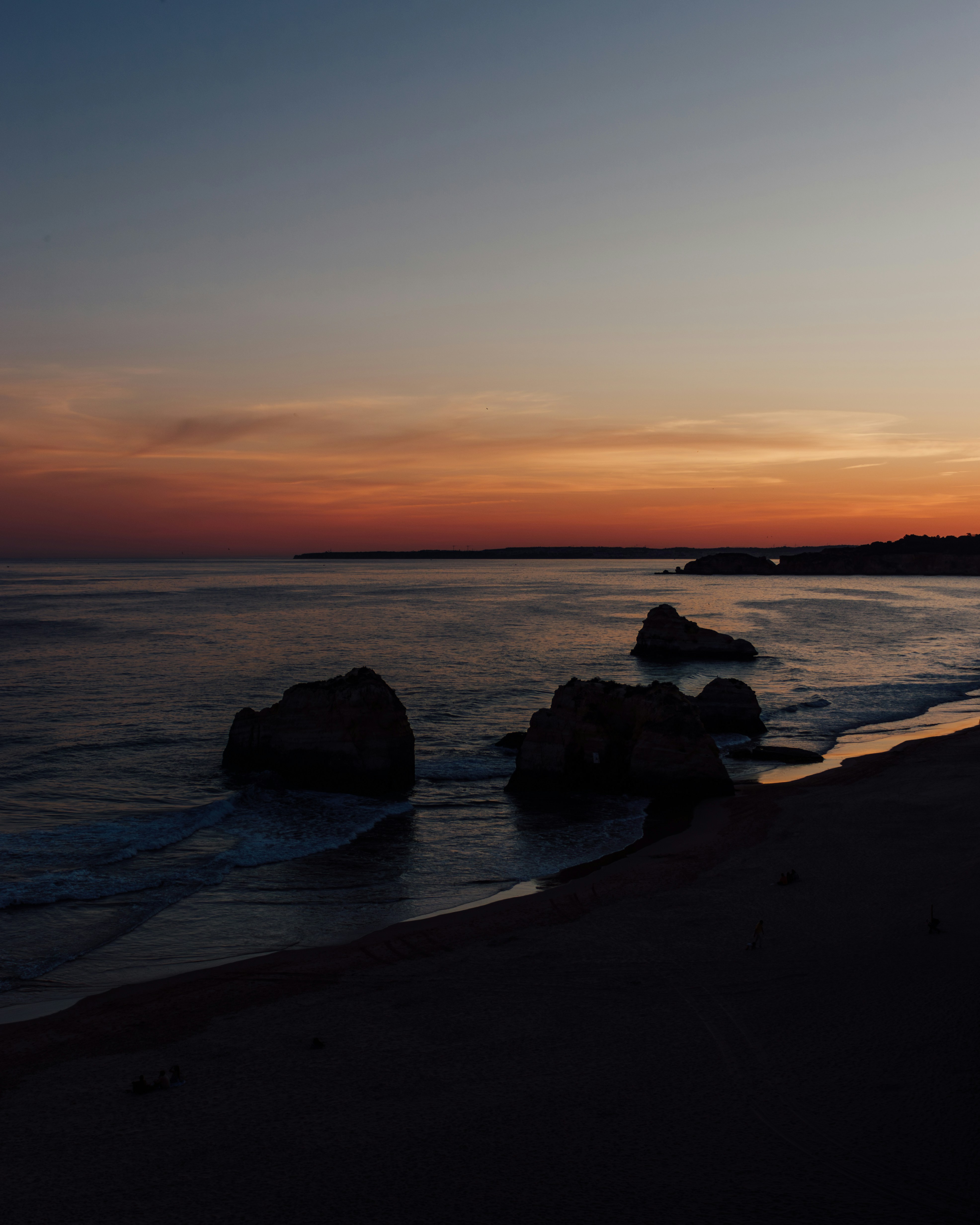 A person standing on a beach at sunset
