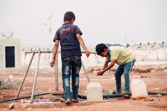 A couple of men standing on top of a dirt field