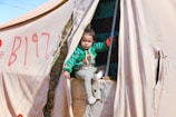 A little boy sitting inside of a tent