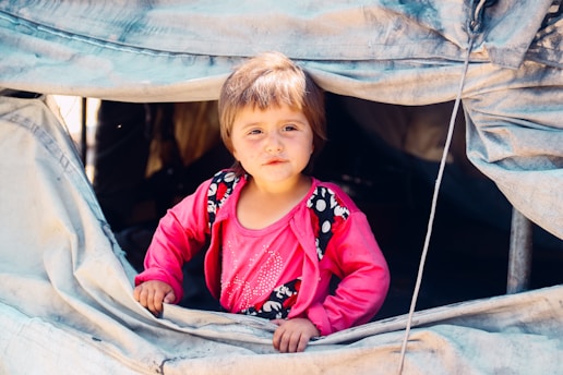 A little girl sitting inside of a tent