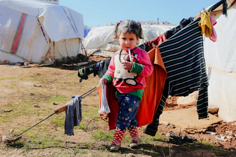 A little girl standing next to a pile of clothes