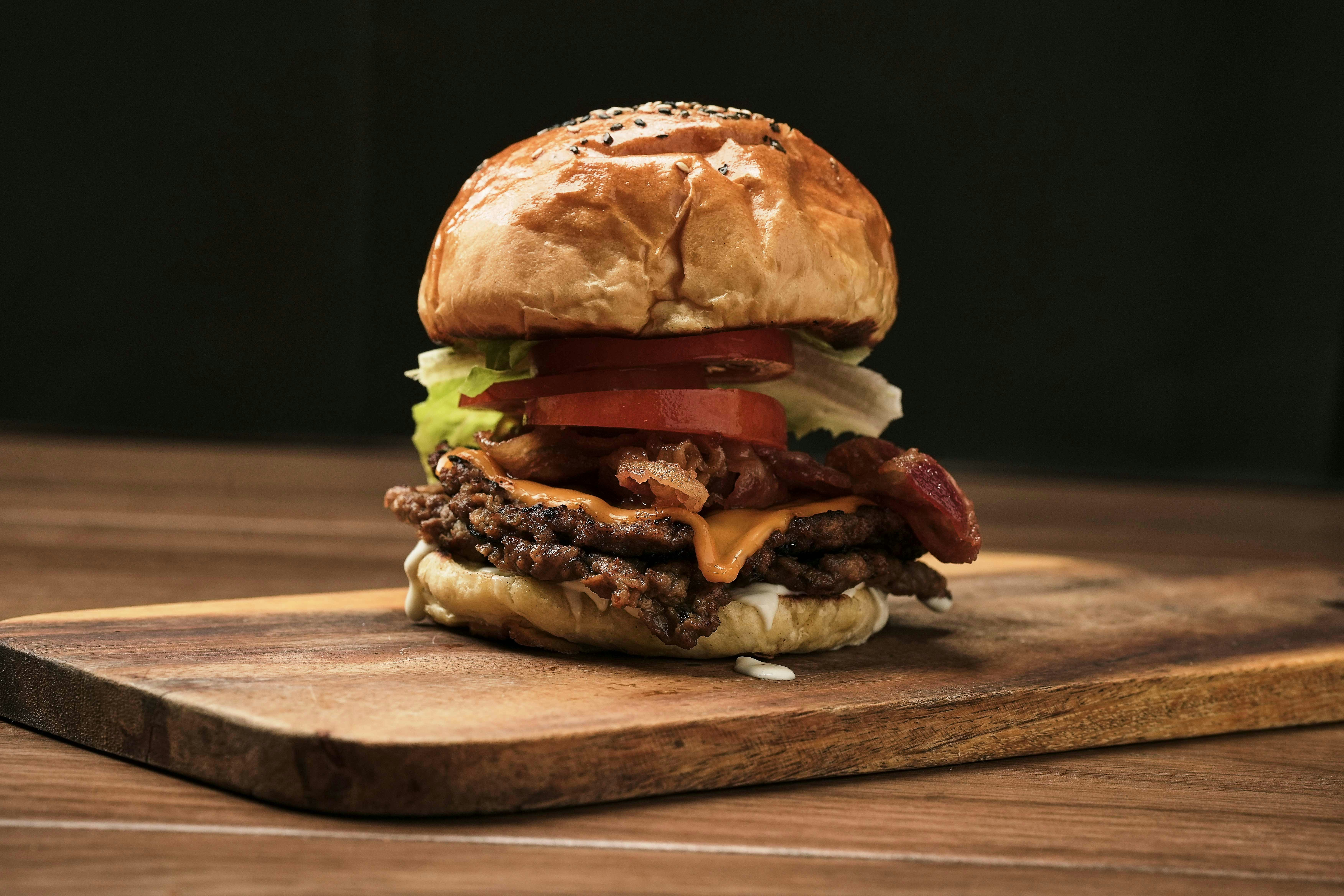A large hamburger sitting on top of a wooden cutting board