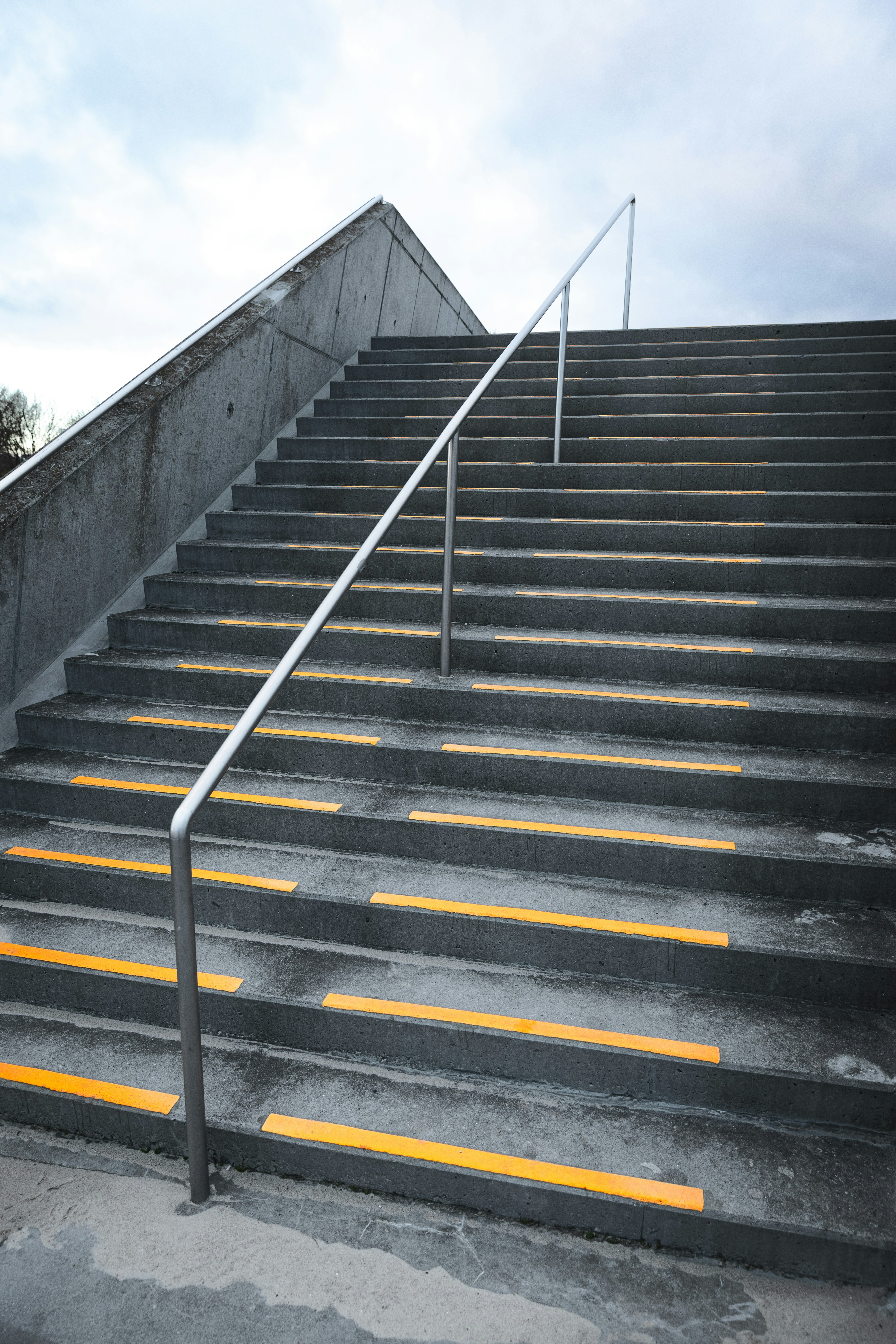 worn concrete steps with a rail and yellow tape on edges of steps