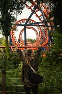 A woman standing in front of a roller coaster