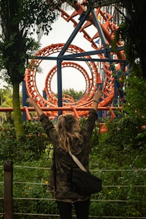 A woman standing in front of a roller coaster