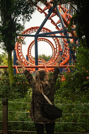 A woman standing in front of a roller coaster