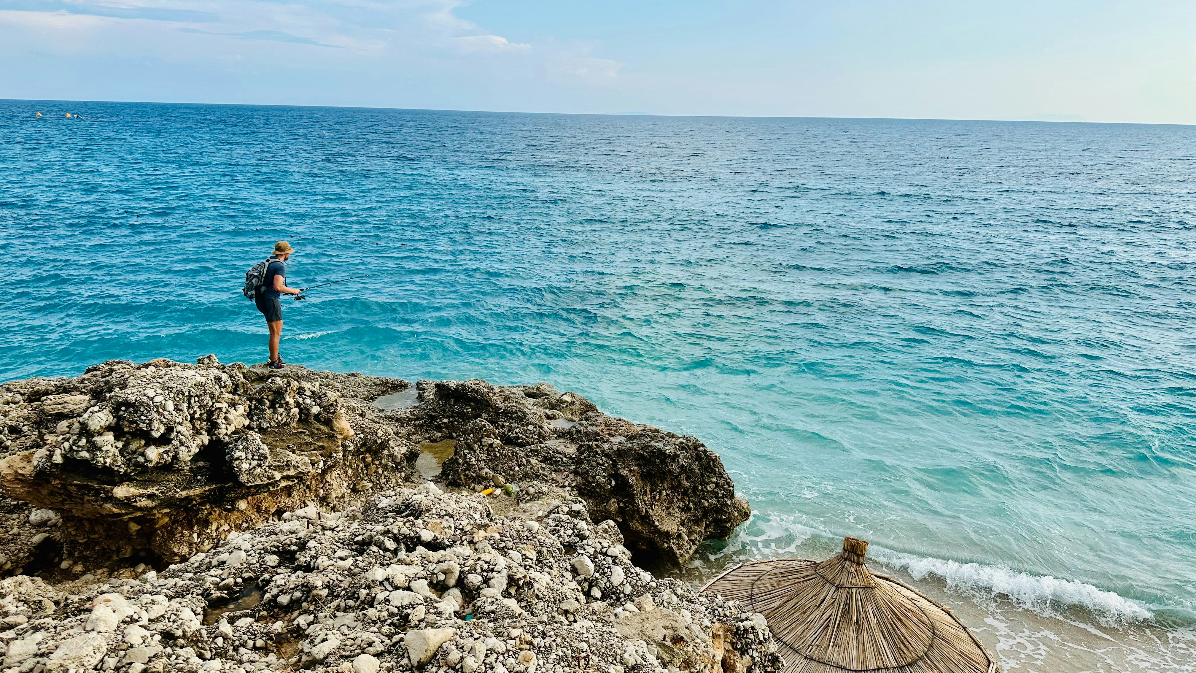 A man standing on top of a cliff next to the ocean