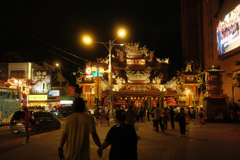 Couple holding hands on a busy street at night