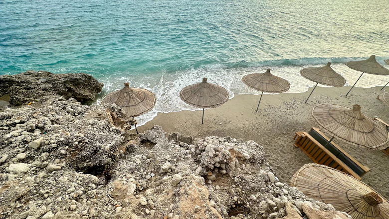 Parasols en strandstoelen op het strand bij Himarë