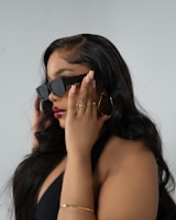 A woman in a black dress holding a pair of sunglasses