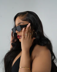 A woman in a black dress holding a pair of sunglasses