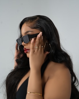 A woman in a black dress holding a pair of sunglasses